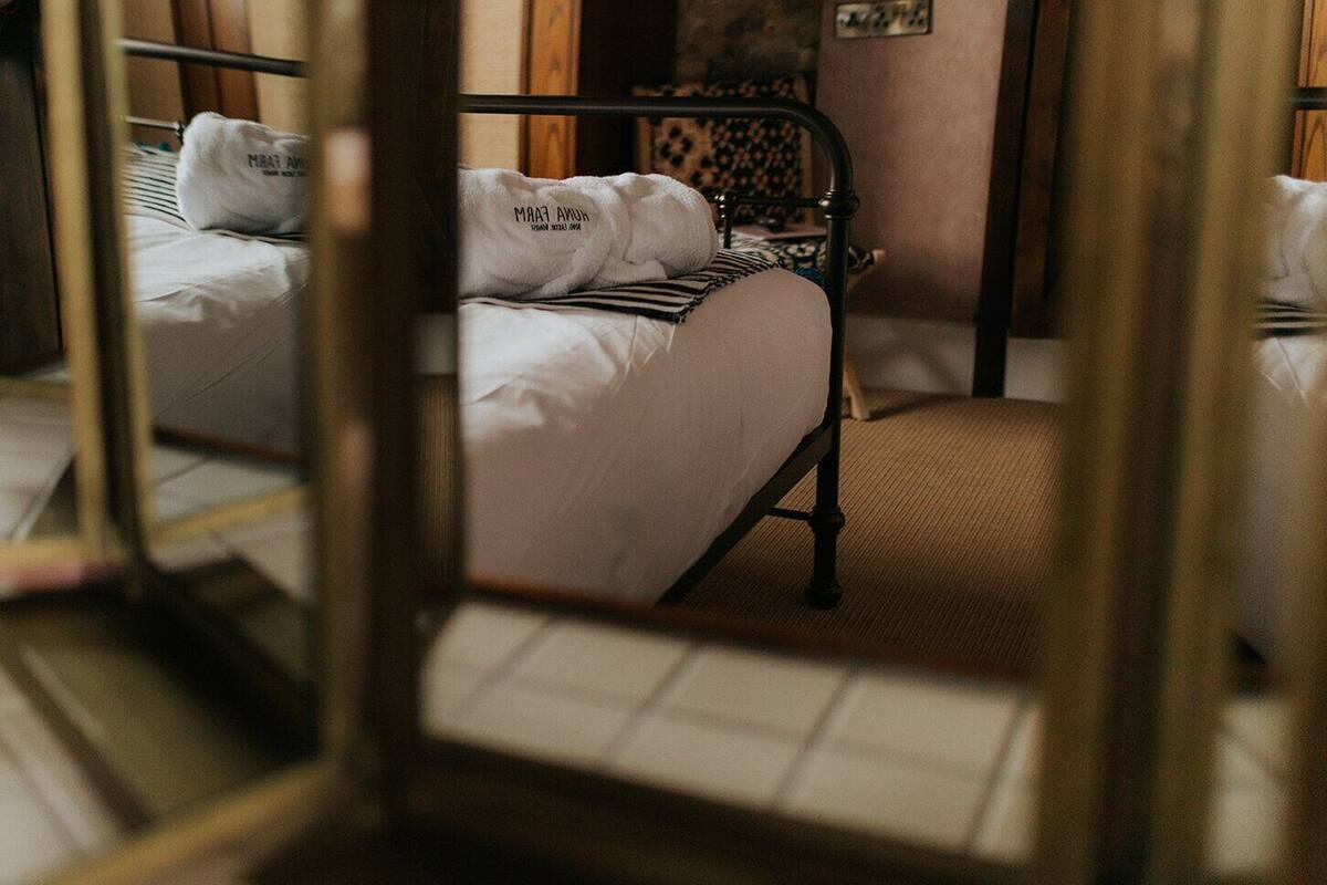 A room with a metal-framed bed, white bedding, and a white towel with text.