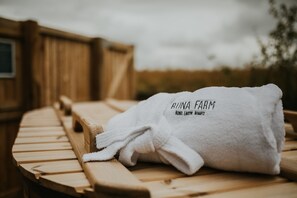 A wooden bench with a white towel labeled "RINNA FARM" and "BOHO. LANTERN. BRIGHT."