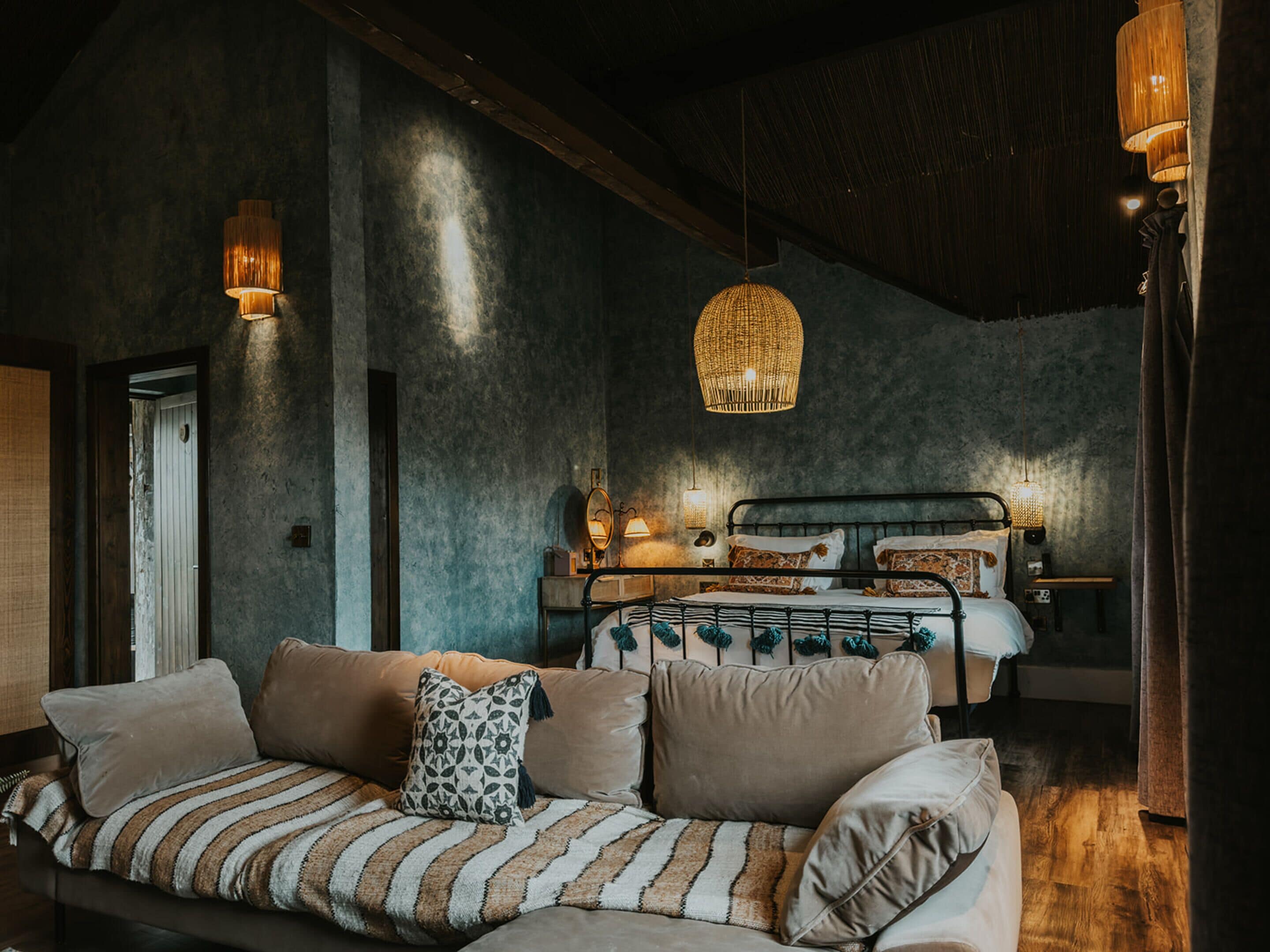 A cozy bedroom with a bed, a sofa, and a hanging light fixture.