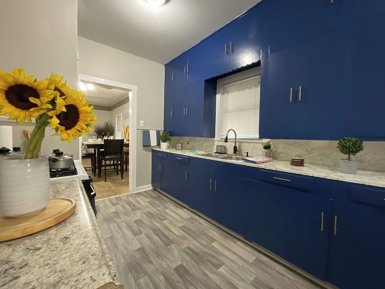 Una cocina moderna con armarios azules, encimera de mármol y suelo de madera.