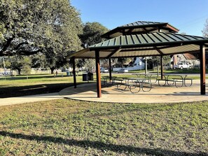 A park with a covered pavilion, picnic tables, and a grassy area.