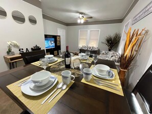 A dining area with a dark wooden table set for four, surrounded by chairs.