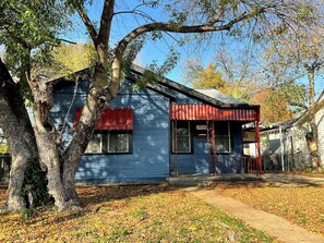A blue building with a red awning, surrounded by trees and a leaf-covered ground.