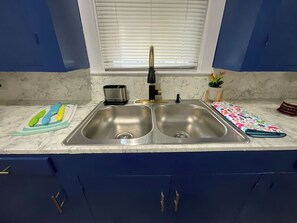 A kitchen with a double sink, a window above, and a marble countertop.