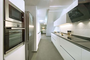 A modern kitchen with stainless steel appliances, white cabinetry, and a black countertop. - Salobre La Isla 8 (Maspalomas)