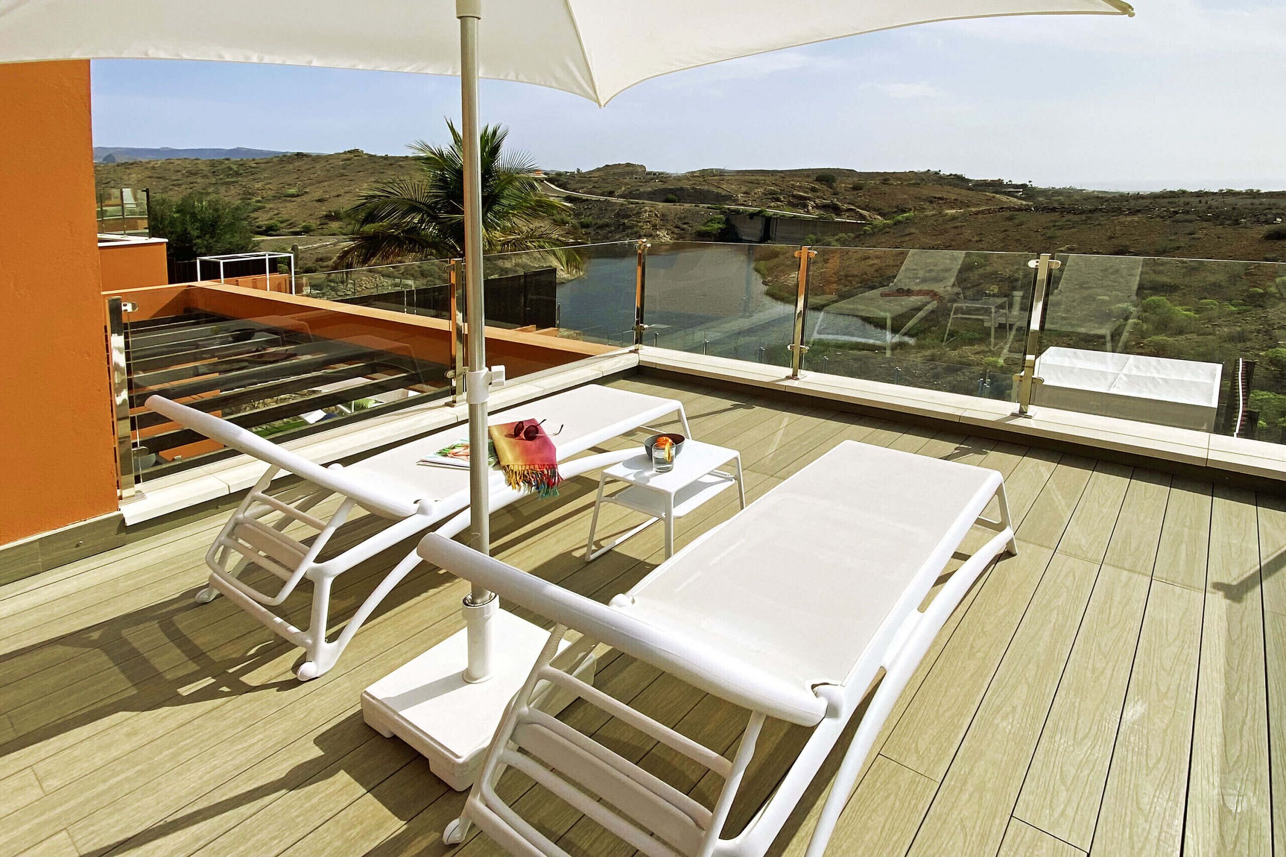 Una terraza en la azotea con tumbonas, una mesa con vela y vistas al paisaje.