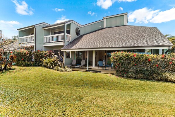 A two-story building with a flat roof, a covered porch, and a landscaped front yard.