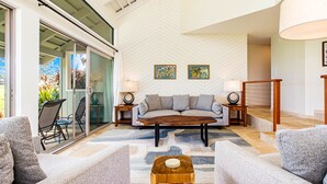 A modern living room with a sofa, two armchairs, a coffee table, and a glass door leading to an outdoor area.