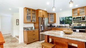 A modern kitchen with wooden cabinets, a stainless steel refrigerator, a built-in oven, and a granite countertop.
