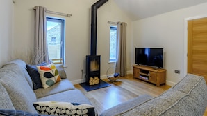 A modern living room with a sofa, a television, a fireplace, and a window. - 2 bedroom accommodation in Thornton le Dale, near Pickering (Thornton le Dale, near Pickering)