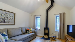 A living room with a sofa, a painting, a fireplace, and a TV. - 2 bedroom accommodation in Thornton le Dale, near Pickering (Thornton le Dale, near Pickering)