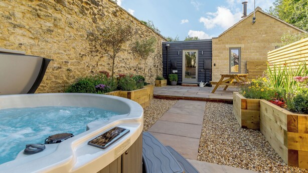 A hot tub, wooden deck, stone wall, and a small building with a door and window. - 2 bedroom accommodation in Thornton le Dale, near Pickering (Thornton le Dale, near Pickering)
