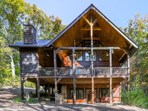 A two-story log cabin with a balcony and a chimney.