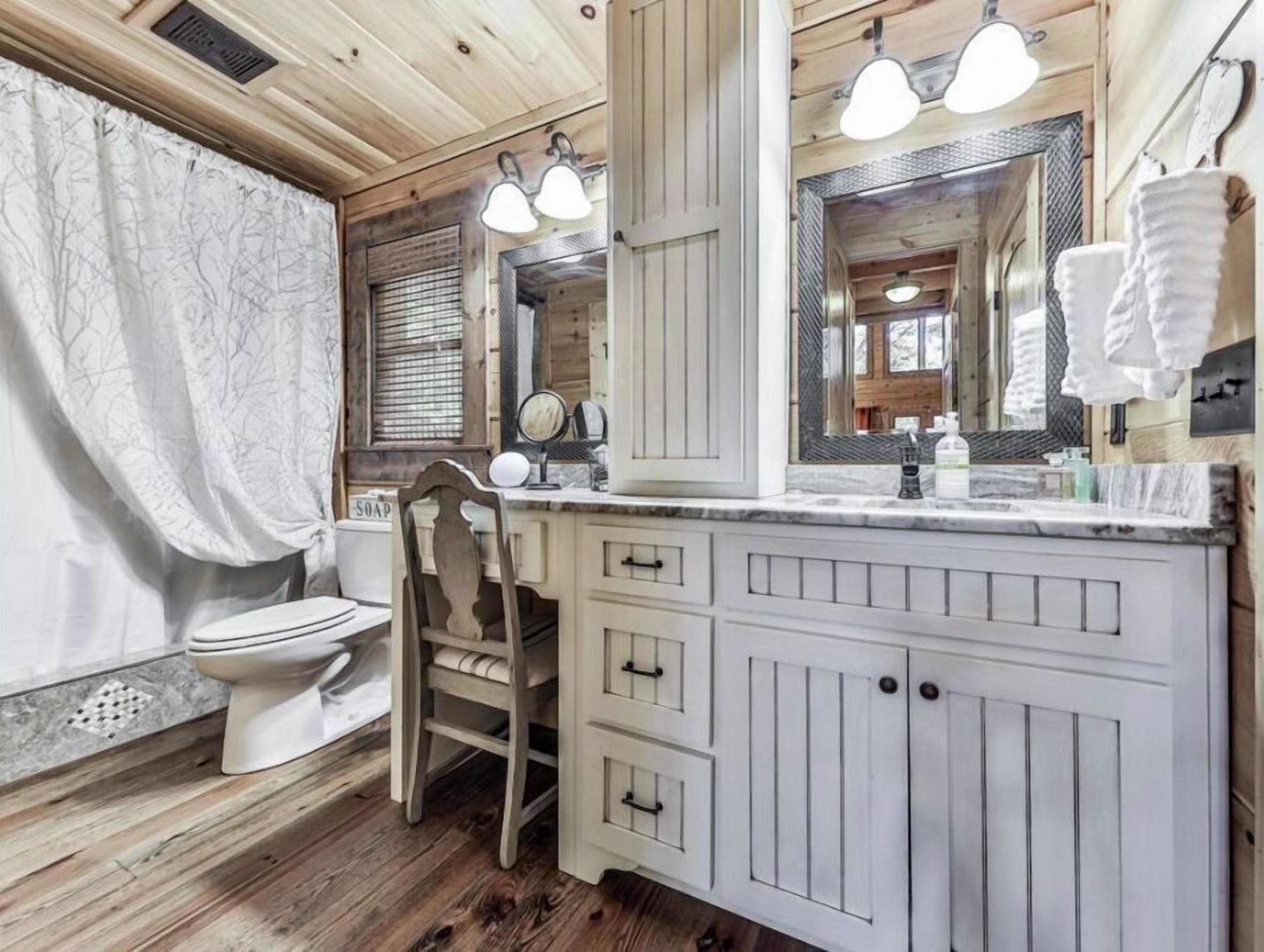 Une salle de bain avec un meuble-lavabo en bois, des toilettes, un miroir et un rideau de douche.