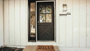 A black door with a window, a 'HELLO' mat, and a sign indicating 'Suite A 414'. - Spacious 4 bedroom Guest House (Clare)