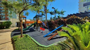 A playground with slides and climbing structures, surrounded by greenery and buildings. - Nautilus Concept - Penha-SC (Penha)