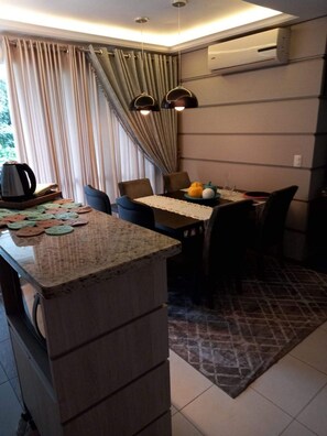Una cocina compacta con zona de comedor, que incluye una cafetera, un frutero y un tapete estampado.