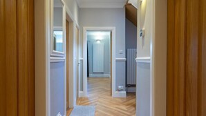 A hallway with wooden paneling, a light-colored floor, and a door leading to a room with a radiator. - Immaculate Family sized holiday home located 10mins from beachfront! (Edinburgh)