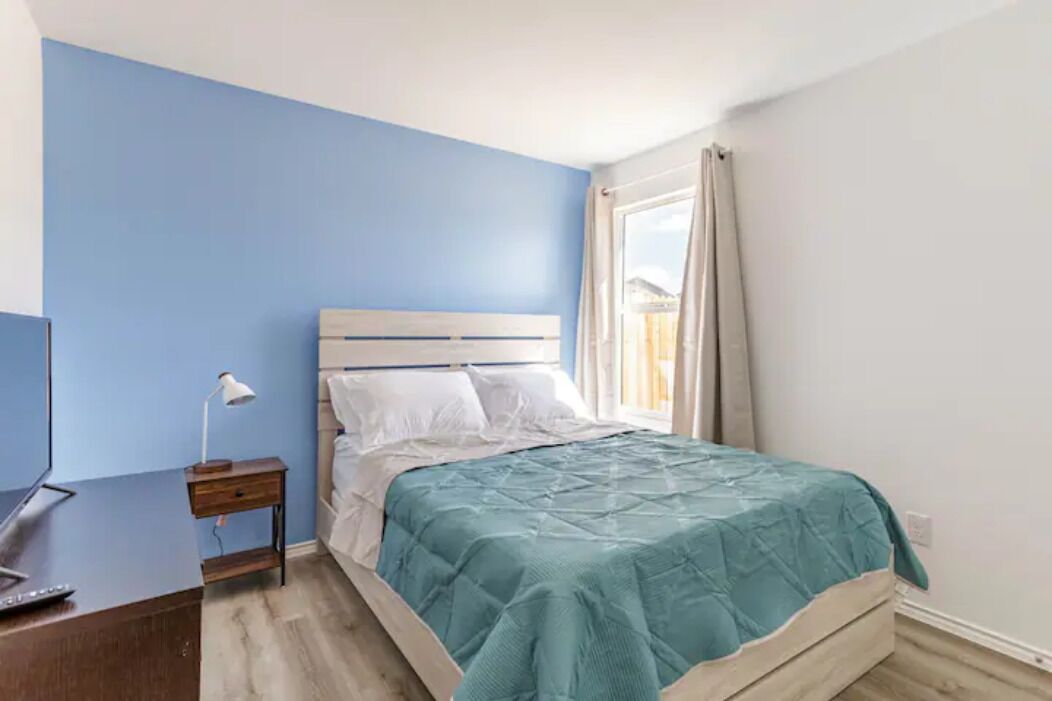 A bedroom with a bed, a desk, and a lamp.
