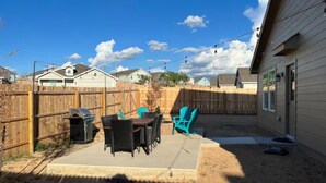 A backyard patio with a table and chairs, a barbecue grill, and a wooden fence. - Spacious, NEW Home with Gorgeous Edison Patio (San Antonio)