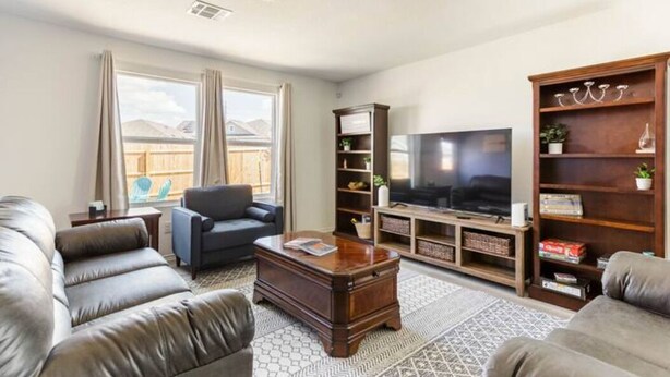 A living room with leather sofas, a coffee table, a TV, and a bookshelf. - Spacious, NEW Home with Gorgeous Edison Patio (San Antonio)