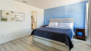 A bedroom with a bed, a nightstand, a wall-mounted lamp, and a painting. - Spacious, NEW Home with Gorgeous Edison Patio (San Antonio)