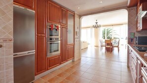 Une cuisine dotée de meubles en bois, d’un réfrigérateur en acier inoxydable et d’un coin repas agrémenté d’un lustre.