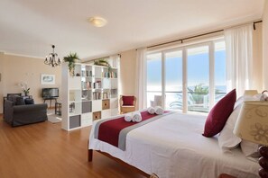 A hotel room with a large bed, a bookshelf, a desk, and a view of the ocean. - Casa del Mar - An Amazing Villa w/ Sea View & Pool (Luz)