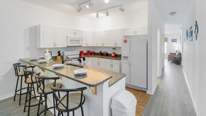 A modern kitchen with white cabinets, a granite countertop, and a central island with bar stools. - Huge screened patio that overlooks Lake Buck, near famous attractions!! (Kissimmee)