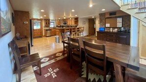 A spacious kitchen with wooden cabinets, a dining area with a large table and chairs, and a staircase leading to an upper level. - Mountain Vintage Vacation Home! Conveniently in Mt CB, easy access to trails! (Crested Butte)