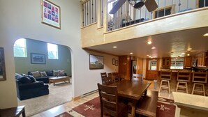 A spacious living area with a dining table, chairs, a sofa, and a staircase leading to an upper level. - Mountain Vintage Vacation Home! Conveniently in Mt CB, easy access to trails! (Crested Butte)
