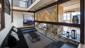 A spacious living area with a stone wall, a black sofa, and a patterned rug. - Bryce Resort Retreat in Shenandoah w/ Amazing Views  (Basye)