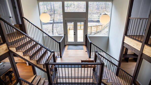 A modern interior with a wooden staircase, large windows, and a view of the outdoors. - Bryce Resort Retreat in Shenandoah w/ Amazing Views  (Basye)
