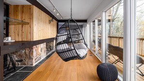 A modern interior with a hanging chair, stone wall, wooden floor, and large windows. - Bryce Resort Retreat in Shenandoah w/ Amazing Views  (Basye)