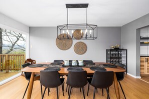 Un coin repas avec une table en bois, des chaises noires et un lustre moderne.