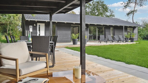 A covered outdoor seating area with a wooden table, chairs, and a book. - Gorgeous home in Oksbøl with sauna (Oksbøl)