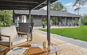 A covered outdoor seating area with a wooden table, chairs, and a book. - Gorgeous home in Oksbøl with sauna (Oksbøl)