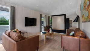 A modern living room with a flat-screen TV, two leather sofas, a wooden coffee table, and a large mirror. - Gorgeous home in Oksbøl with sauna (Oksbøl)
