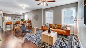 A modern living room with a sofa, coffee table, and dining area. - Oakley Square 2BR Condo-Walkable with Free Parking (Cincinnati)