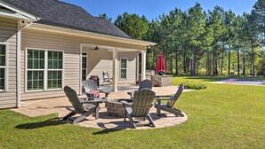 A covered patio area with outdoor furniture, a fire pit, and a grill.