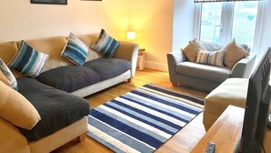 Un salon avec deux canapés, un tapis à rayures et un téléviseur.
