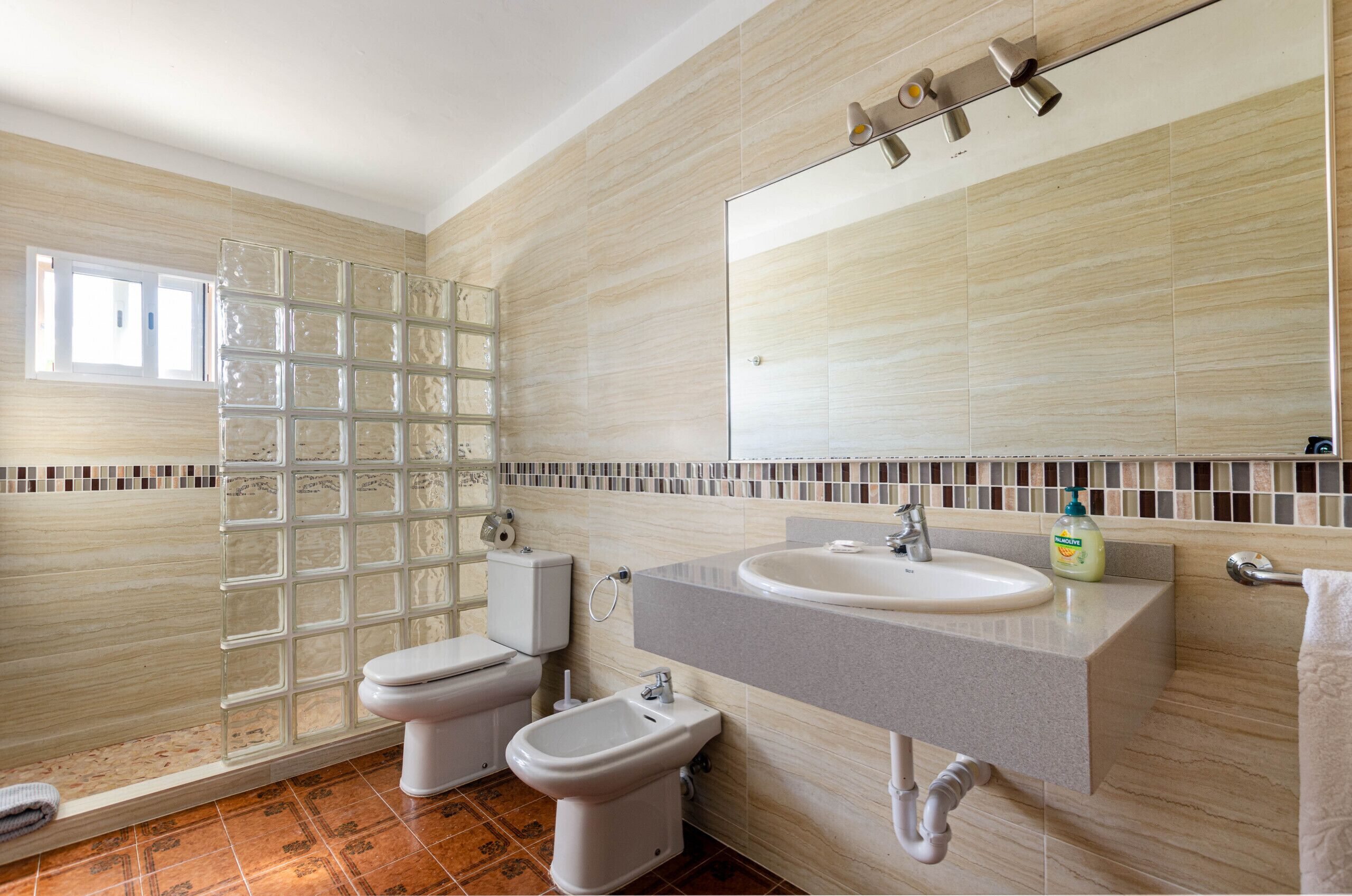 A bathroom with a toilet, bidet, sink, and shower.