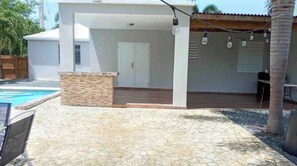 Un patio cubierto con piscina, suelo de piedra y una puerta blanca.