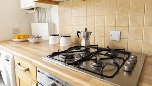 A kitchen with a gas stove, a coffee maker, and a bowl of fruit on the counter. - Bridge View | Oxford Holiday Let | 1 Bed & Sleeps 2 (Oxford)
