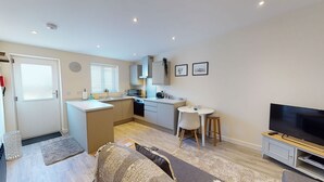 Un apartamento compacto con kitchenette, comedor, sala de estar con sofá y televisión.