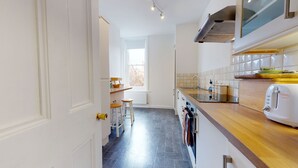 Een moderne keuken met een vloer van zwarte tegels, witte kastjes en een houten aanrecht.