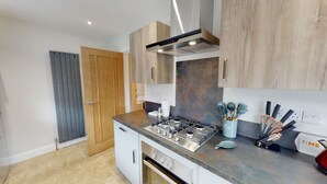 Une cuisine moderne équipée d’une cuisinière à gaz, d’appareils électroménagers en acier inoxydable, de meubles en bois et d’un plan de travail bleu.