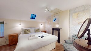 A neatly arranged bedroom with a bed, bedside tables, a dresser, a mirror, and a wall-mounted light fixture.