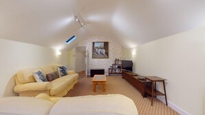 A spacious living room with a high ceiling, a sofa set, a fireplace, a bookshelf, and a painting on the wall.