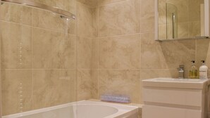 Une salle de bain avec une baignoire, une douche et un miroir.